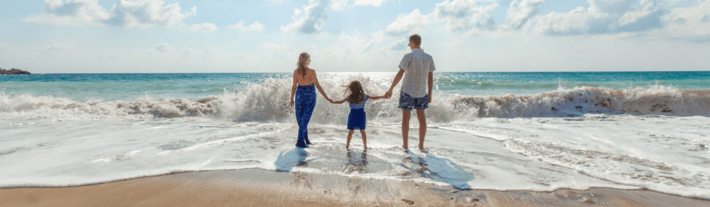 mor, far og barn holder i haand på stranden ude i vandet