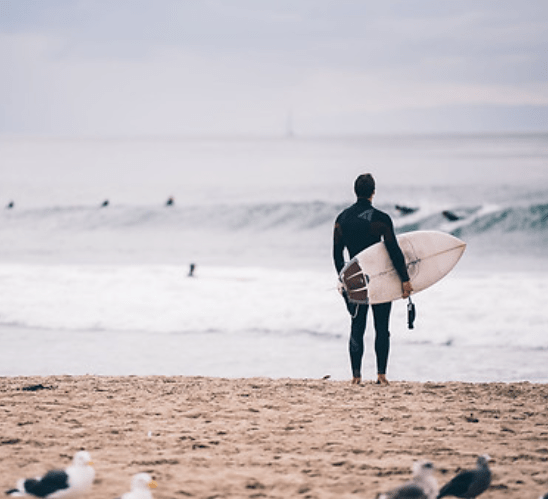 mand staar med SUP-board ved havet